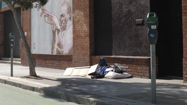 A homeless man sleeping on the pavement outside the headquarters of BetterUp 
